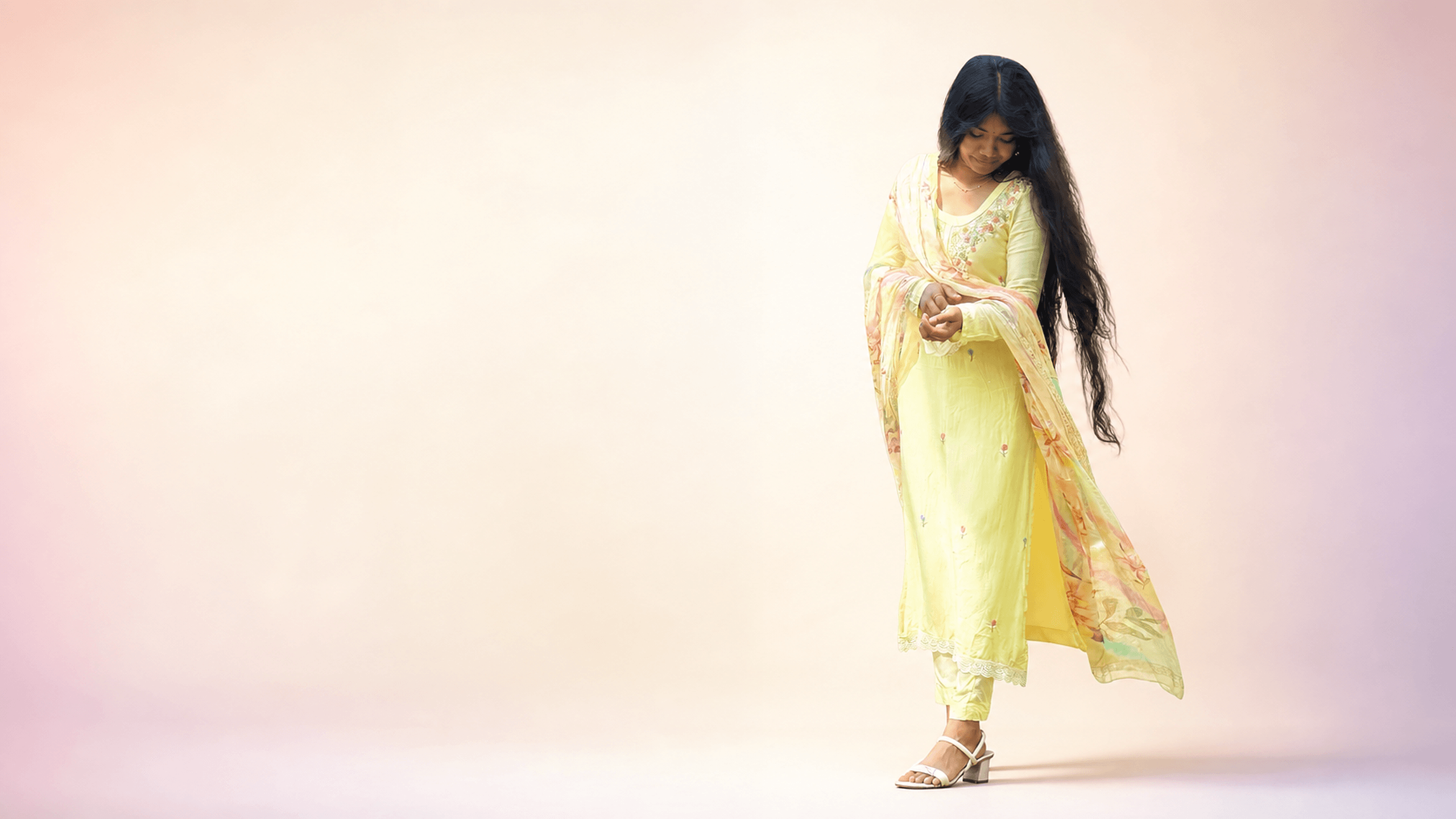 Woman wearing a pastel yellow embroidered churidar set from DZANE